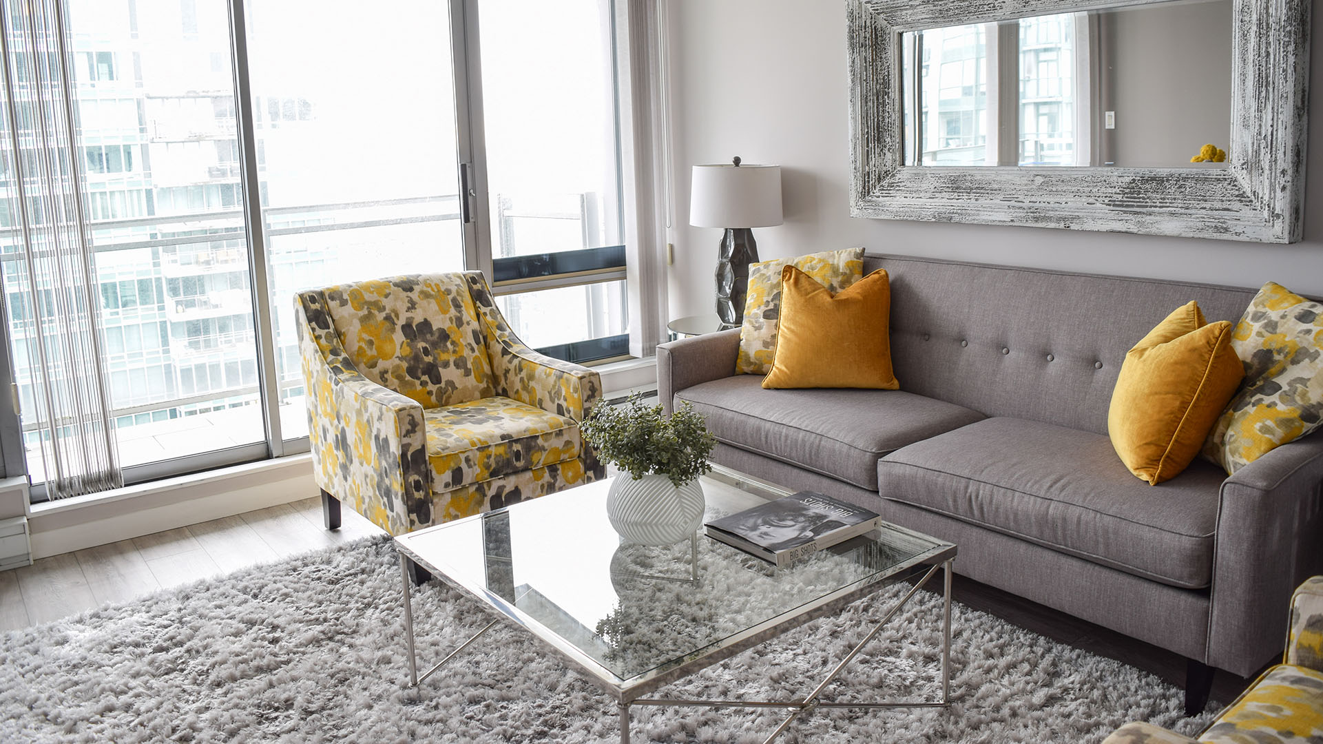 Grey sofa, pattern accent chair, and a glass coffee table in the living room of apartment 3203-1288 West Georgia, at the Residences on Georgia.